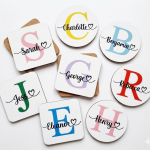 Personalised square and round white coasters featuring colourful initials and script names, highlighting the 4mm thickness and cork backing.