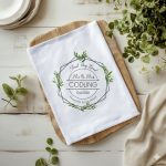 Personalised white tea towel with a green leaf wreath design featuring Mr and Mrs Codling Est 2026 and the words Happily Ever After.