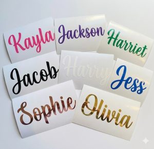 A flat lay arrangement of eight custom permanent vinyl name decals resting on their white backing paper against a clean white background, showcasing the names Kayla, Jackson, Harriet, Jacob, Harry, Jess, Sophie, and Olivia in a variety of glossy and metallic finishes including hot pink, purple, and rose gold.